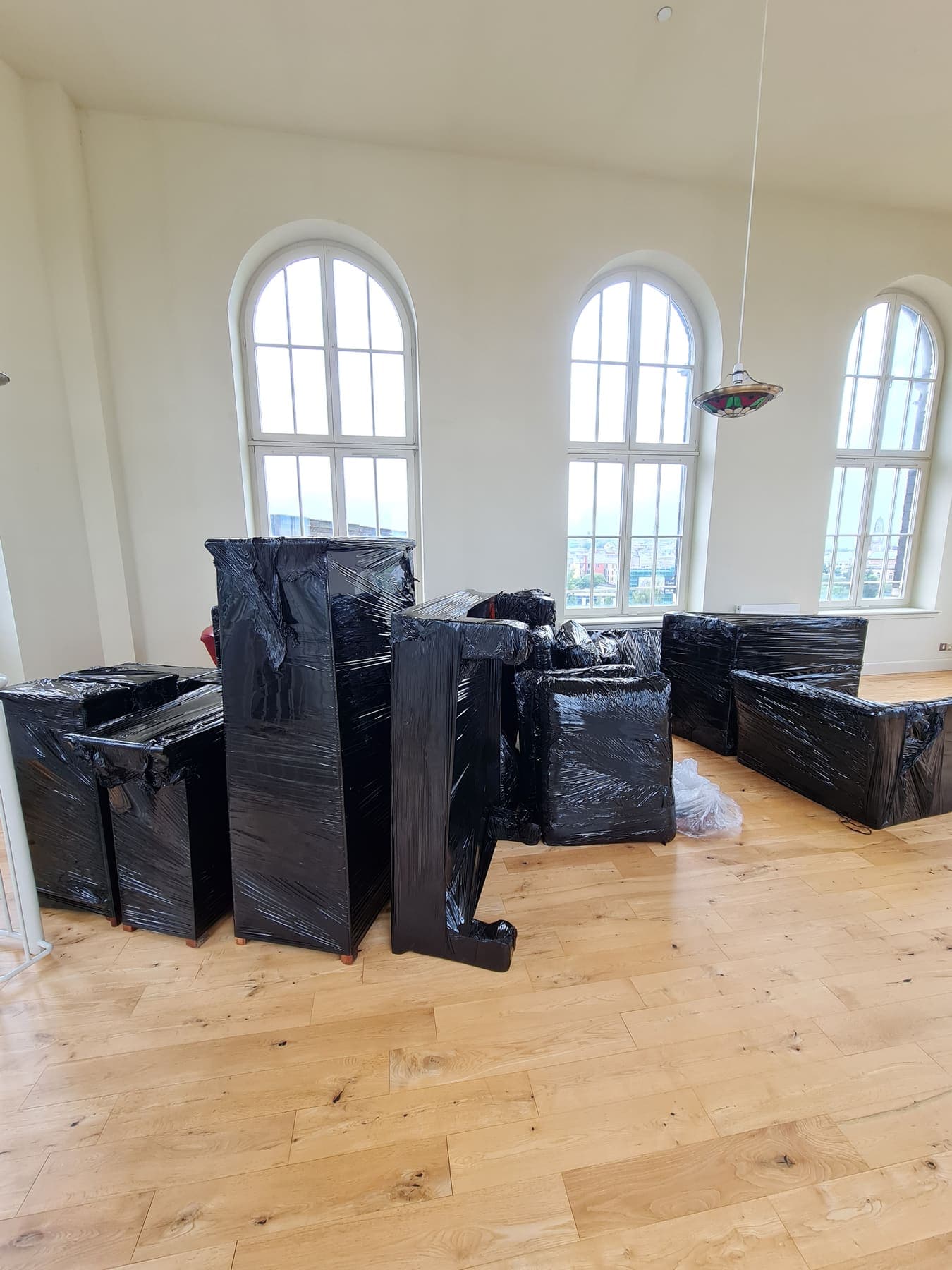 Furniture wrapped and sealed for storage, stacked in a cleared room
