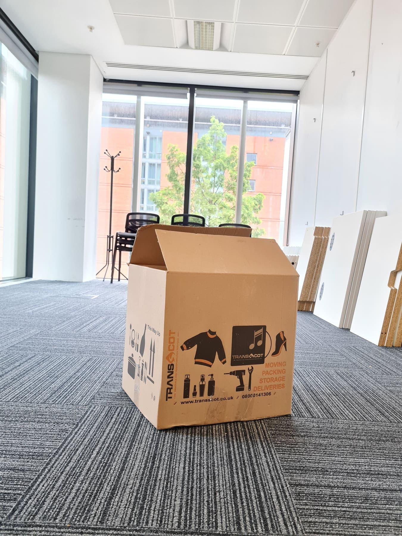A TransScot moving box in an office being cleared, with desks dismantled and stacked behind it